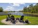 A backyard fire pit with Adirondack chairs offers a peaceful view of the lake at 258 Sandoval Dr, Ormond Beach, FL 32174