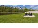 Manicured lawn in backyard featuring a lake, a black metal fence, and a fire pit with chairs at 258 Sandoval Dr, Ormond Beach, FL 32174