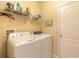 Efficient laundry room includes a side-by-side washer and dryer with shelving above at 2672 Star Coral Ln, New Smyrna Beach, FL 32168