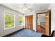 Well-lit bedroom with blue carpet, ceiling fan, two windows, and closet with wood shutter doors at 28 Shadowcreek Way, Ormond Beach, FL 32174
