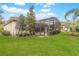 Lush backyard featuring a screened-in lanai, manicured lawn, and mature trees, offering a private and serene outdoor space at 2811 S Asciano Ct, New Smyrna Beach, FL 32168