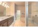 Bathroom with granite countertop vanity, dark wood cabinets, double sinks, and a large walk-in shower at 2811 S Asciano Ct, New Smyrna Beach, FL 32168