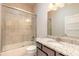 Bathroom featuring a vanity with granite countertop and tub with glass door and tiled surround at 2811 S Asciano Ct, New Smyrna Beach, FL 32168