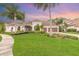 Inviting front yard with lush green grass, swaying palm trees, and a charming home with a terracotta roof at 2811 S Asciano Ct, New Smyrna Beach, FL 32168