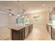 Open kitchen with island, stainless steel appliances, chandelier and sliding glass doors at 2811 S Asciano Ct, New Smyrna Beach, FL 32168