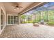 Spacious screened-in patio featuring brick pavers, a fire pit, outdoor grill, and a ceiling fan for comfortable outdoor living at 2811 S Asciano Ct, New Smyrna Beach, FL 32168