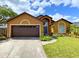 Inviting single-story home with a two-car garage, arched windows, and lush green lawn at 2953 Autumn Run Pl, Orlando, FL 32822