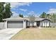 Charming single-story home with a two-car garage, landscaped yard, and gray stucco exterior at 3025 Bonkirk Dr, Deltona, FL 32738