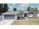 Charming single-story home with a two-car garage, landscaped yard, and gray stucco exterior at 3025 Bonkirk Dr, Deltona, FL 32738