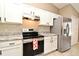 Well-lit kitchen with stainless steel appliances, granite countertops, white cabinets, and tile backsplash at 3025 Bonkirk Dr, Deltona, FL 32738