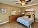 Cozy bedroom features a wooden dresser, mirror, wood-look tile floors, and ceiling fan at 400 Taylorville St, Deltona, FL 32725