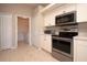 Close up of kitchen with stainless steel oven and microwave, with white cabinets and a view of laundry room at 41 Ormond Green Blvd, Ormond Beach, FL 32174