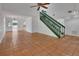 Open-concept living room with tile floors, ceiling fan, and a staircase featuring a green railing at 5265 Myakka Rd, De Leon Springs, FL 32130