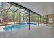 Inviting screened pool area offering a serene escape surrounded by lush greenery, waterfall feature and brick accents at 5265 Myakka Rd, De Leon Springs, FL 32130