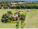 Expansive aerial view showcases an estate home with pool, barn and lush grounds surrounded by green pastures at 5549 Aragon Ave, De Leon Springs, FL 32130