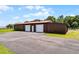 A long metal barn featuring 2 garage doors with a large asphalt parking area at 5549 Aragon Ave, De Leon Springs, FL 32130