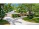 Elegant brick home with a spacious three-car garage and a large driveway, complemented by mature trees and landscaping at 6 Leisure Wood Way, Ormond Beach, FL 32174