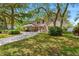 Inviting brick home with a large driveway, complemented by lush landscaping and mature trees, enhancing curb appeal at 6 Leisure Wood Way, Ormond Beach, FL 32174