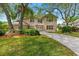 Beautiful brick home featuring arched windows, a lush lawn, and a circular driveway framed by mature trees at 6 Leisure Wood Way, Ormond Beach, FL 32174