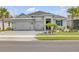 Beautiful single-story home featuring a well-manicured lawn, three-car garage, and charming landscaping with palm trees at 660 Mosaic Blvd, Daytona Beach, FL 32124