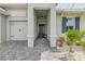 Covered front entrance with stone pavers, decorative light fixture, and view of the three-car garage at 660 Mosaic Blvd, Daytona Beach, FL 32124