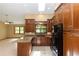 Spacious kitchen featuring granite countertops, wood cabinets, black appliances, and tile flooring, perfect for cooking at 68 Spring Lake Dr, Debary, FL 32713