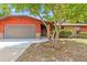 Charming home exterior showcasing a spacious garage, red siding, brick accents, and inviting front entrance at 688 Cumberland Rd, Deland, FL 32724