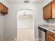 Open kitchen view into adjacent tiled living area with an arched doorway, stainless steel appliances, and stone countertops at 688 Cumberland Rd, Deland, FL 32724