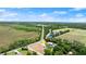 An aerial view of the home, positioned with views of a long road with farm fields and sports fields beyond at 793 Timothy St, Ormond Beach, FL 32174