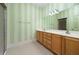 Bathroom featuring dual sinks, wood cabinets, tile floors and striped accent wall at 8231 Sw 79Th Ct, Ocala, FL 34476