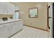 Well-lit kitchen features white cabinets, stainless steel refrigerator, and a view to the bathroom at 941 Village Lake N Dr, Deland, FL 32724