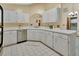 Bright kitchen features white cabinets, tiled floors, stainless steel dishwasher, and neutral countertops at 941 Village Lake N Dr, Deland, FL 32724