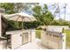 Outdoor kitchen with built-in BBQ and mini fridge, ideal for entertaining in the backyard at 10 Foxhunter Flt, Ormond Beach, FL 32174
