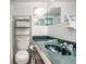 Clean bathroom with white tile, an emerald green countertop and sink, and storage shelves at 1233 N Atlantic Ave # 3090, Daytona Beach, FL 32118