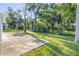 Open backyard with mature trees, lush green grass, and a large patio area at 128 Oakridge Ave, Edgewater, FL 32132