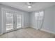 Bright bedroom featuring tiled flooring, ceiling fan, and glass paneled double doors to the exterior at 128 Oakridge Ave, Edgewater, FL 32132