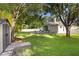 Beautifully landscaped backyard featuring green grass, privacy fence, shade trees, and a view of the home's exterior at 1523 Red Plum Holw, Deland, FL 32720
