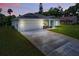 Inviting single-story home featuring a two-car garage, wide driveway, and beautifully landscaped front yard at dusk at 156 N Cory Dr, Edgewater, FL 32141