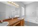 Bathroom featuring double sinks with wood cabinets, a block glass window, and shower at 15733 Green Point Ct, Clermont, FL 34714