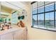 Bathroom featuring a single sink vanity, a large mirror, and a large window at 1613 Crescent Ridge Rd, Daytona Beach, FL 32118