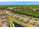 Nice aerial view of a community with terra cotta roofs, manicured lawns, a pond, and a backdrop of dense trees at 163 Rosa Bella Vw, Debary, FL 32713