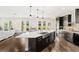 Open kitchen featuring dark cabinets, large island with sink, stainless appliances, and a seamless flow to living spaces at 163 Rosa Bella Vw, Debary, FL 32713