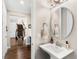 Stylish powder room with pedestal sink, round mirror, and wood floors leading to the staircase at 163 Rosa Bella Vw, Debary, FL 32713