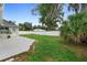 Well-maintained backyard with green grass, white fence, and tropical trees at 1715 Queen Palm Dr, Edgewater, FL 32132