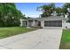 Well-kept single-story home with green lawn, charming walkway, and a screened garage at 1715 Queen Palm Dr, Edgewater, FL 32132