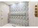 Modern bathroom with rainfall shower head, leaf-patterned tiles, a shower bench, and gold fixtures at 1841 Spruce Creek Blvd, Port Orange, FL 32128