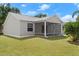 A view of the back exterior with a well-maintained lawn and screened-in patio at 1930 Harston Trl, The Villages, FL 32162