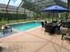 Relax in the screened-in pool and spa area with dining, lounge seating, and lush landscaping at 201 Asterbrooke Dr, Deland, FL 32724
