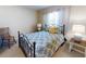 Comfortable bedroom with a blue patterned comforter on a black iron bed frame, a side table, and a wooden chair at 2101 N Atlantic Ave # 10, Daytona Beach, FL 32118