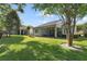 The backyard features a covered patio, lush green grass, and mature trees at 220 Asterbrooke Dr, Deland, FL 32724